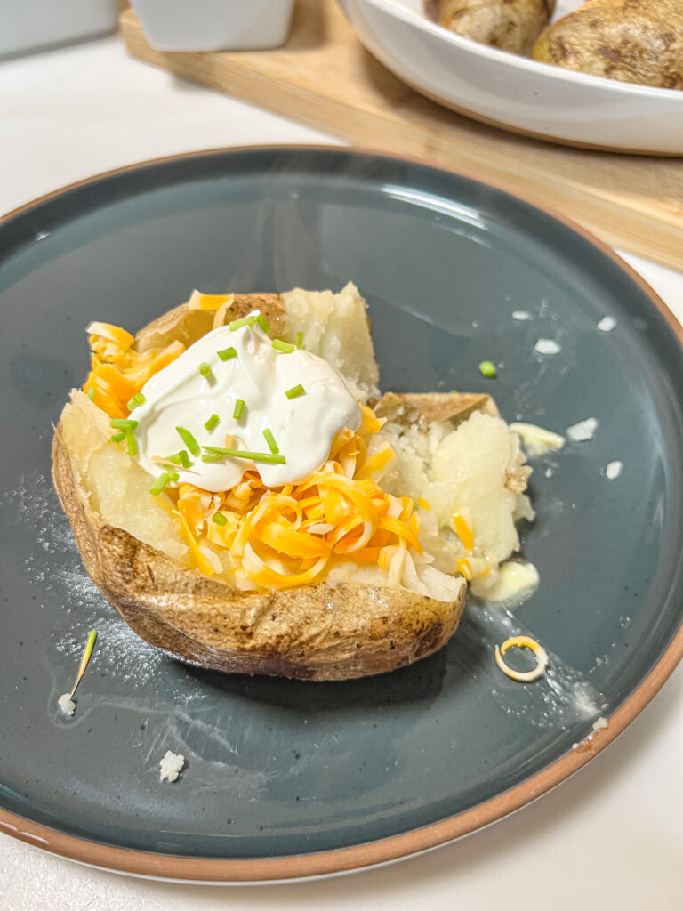 Steaming hot potato with butter, cheese, sour cream, and chives.