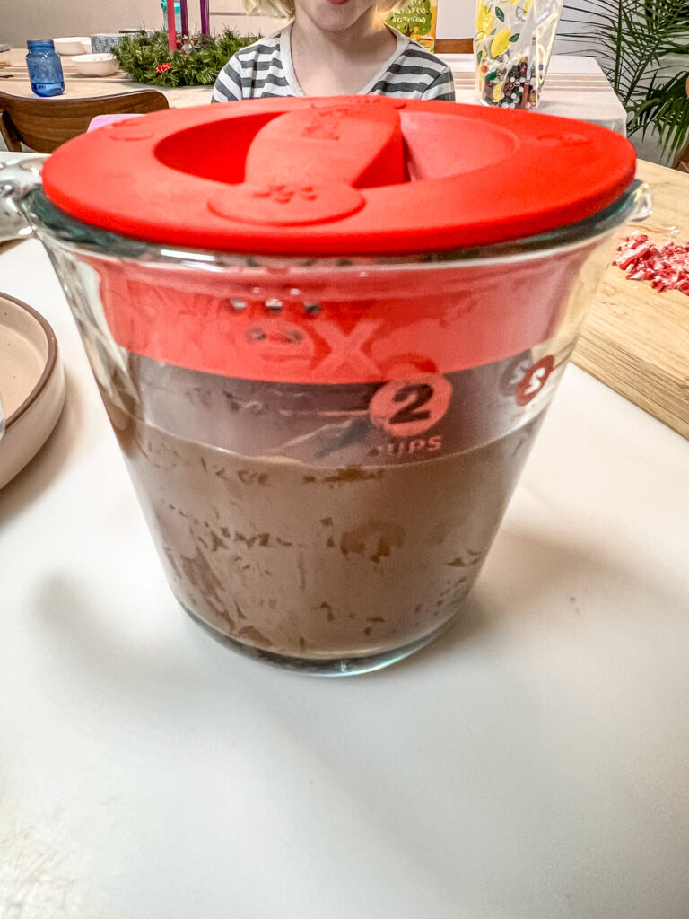 Chocolate in a microwave safe measuring cup, with a pour spout and the lid on (for storage).