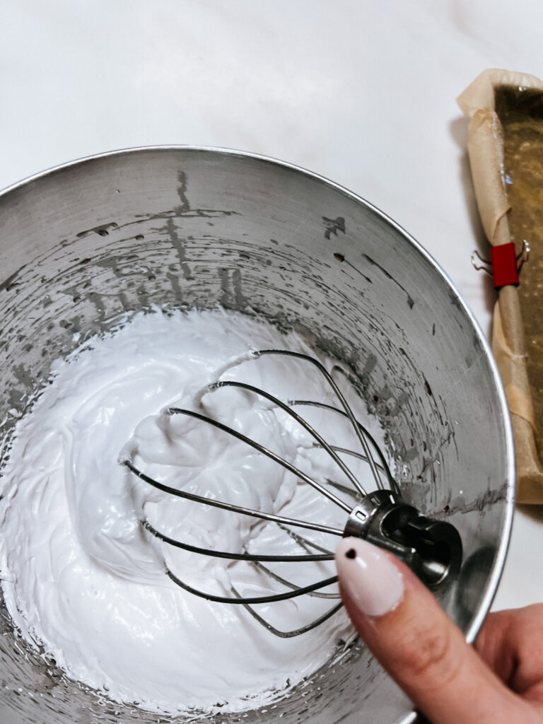the finished marshmallow mixture before it sets. Still in the mixing bowl with the whisk attachment, the color is more white with a very slight pink hue.