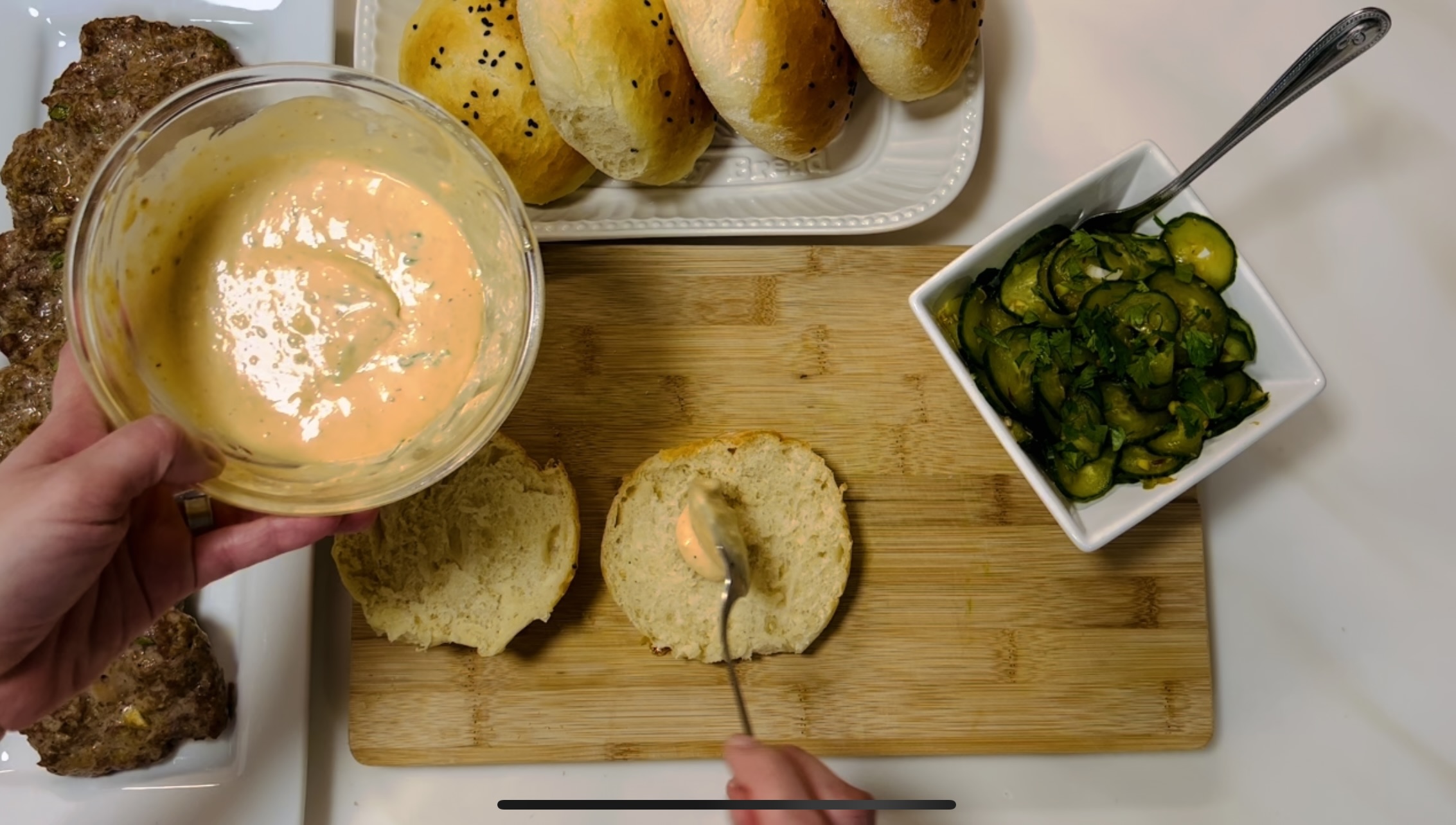 Spreading the remoulade onto both side of the burger bun