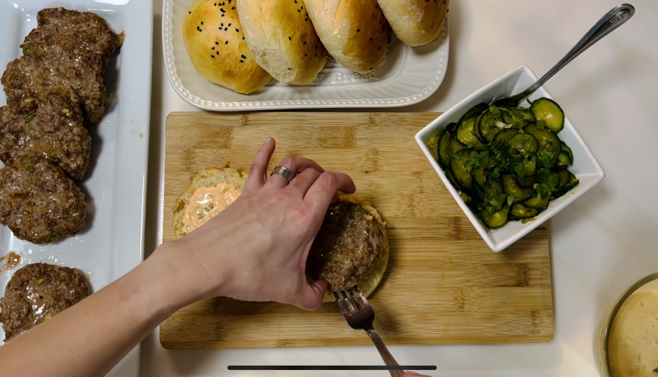placing the pork burger onto the sauced bun