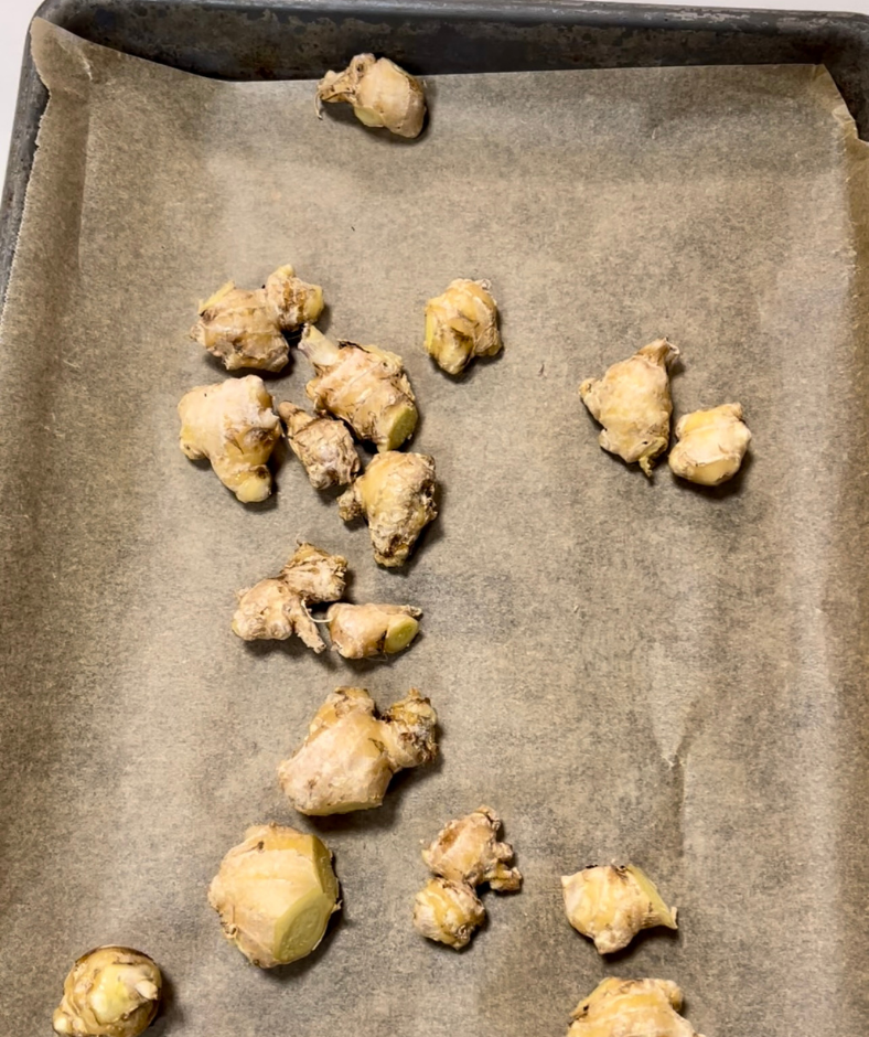cut ginger laying on a baking sheet lined with parchment paper