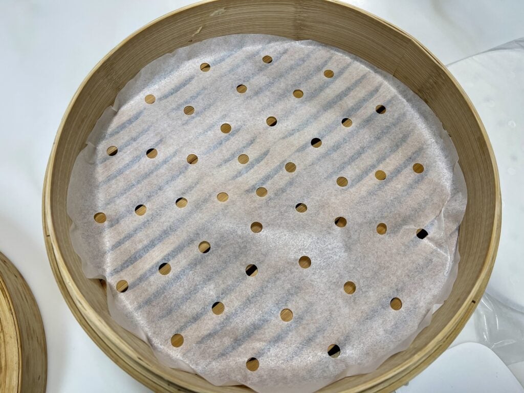 bamboo steamer basket lined with parchment paper for steaming bao buns
