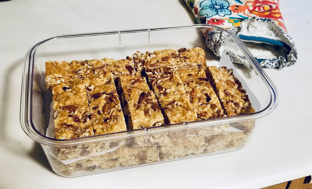 A close up image of the bars (light brown in color with pecans on top), with the title as follows: Jenn's Versatile Snack Bars (Sure to satisfy ANY tummy).