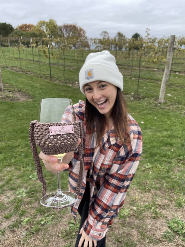 Wine Glass Lanyard around a stemmed wine glass being held by a brunette young women in plaid and a white knit hat.