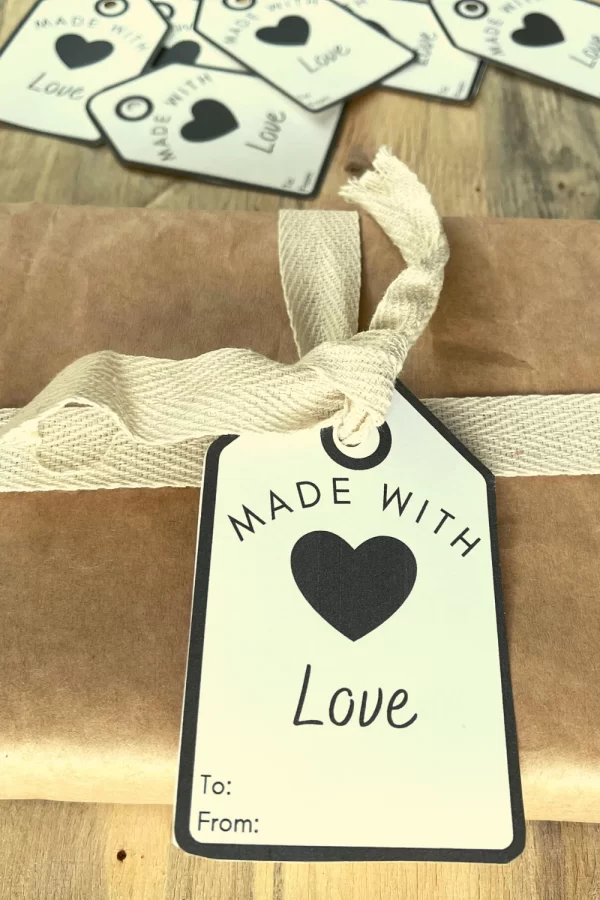 Made with love tags being displayed as the would be used. One is tied to a brown paper wrapped package and others are laying around.