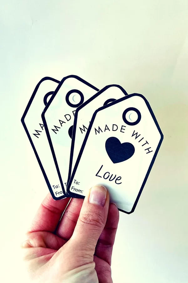 Made with love tags being held by one hand, fanned out.