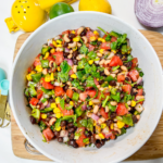 Finished cowboy caviar in a ceramic bowl served on bamboo board