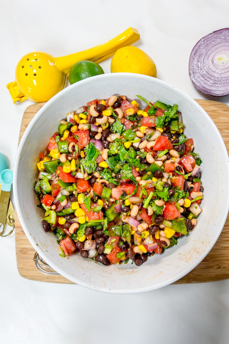 Finished cowboy caviar in a ceramic bowl served on bamboo board