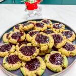 A snow man figuring behind a plate of Matcha Almond Butter Thumbprints.