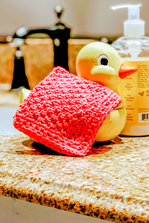 Image of the Finished wash cloth in peach on a porcelain yellow duck