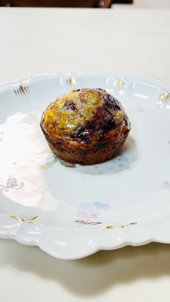 A single wild Black raspberry orange muffin finished a delicate white porcelain plate