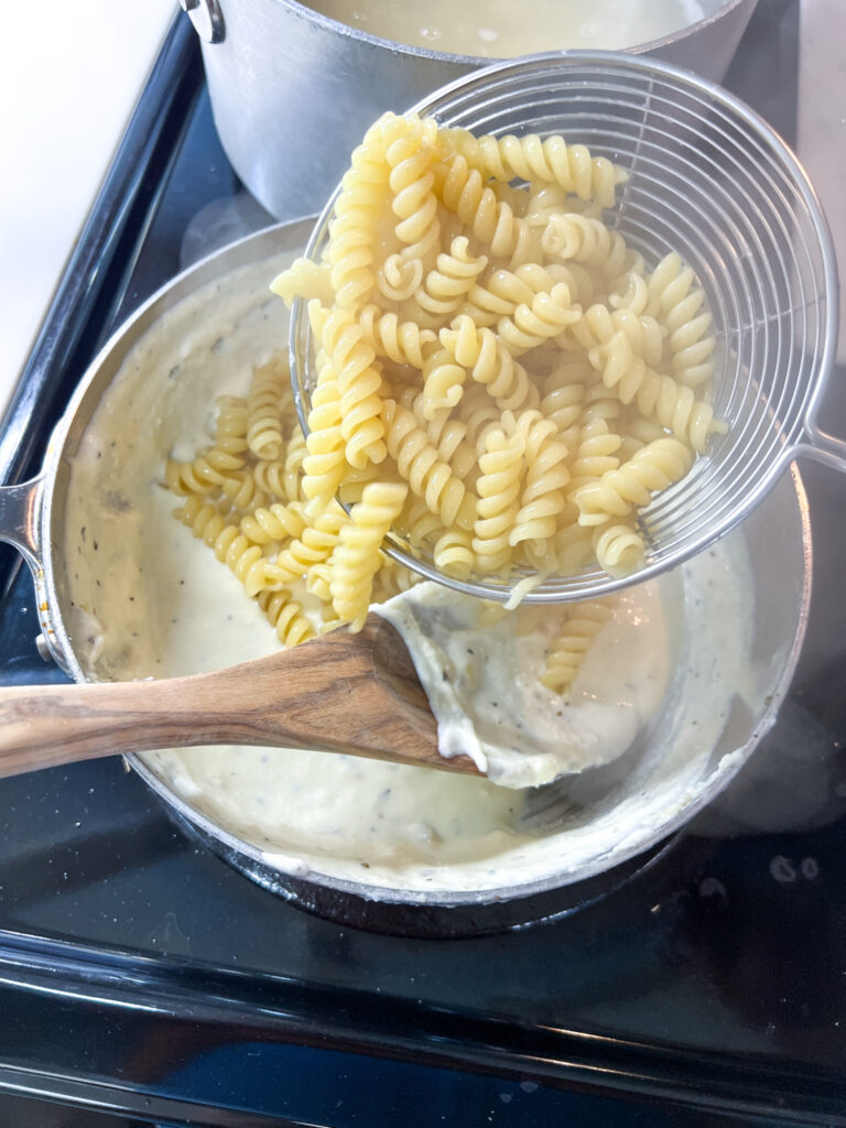 adding the pasta to the alfredo