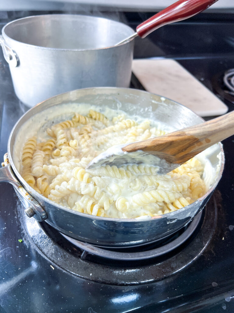 pasta mixed with the alfredo sauce in a pan.
