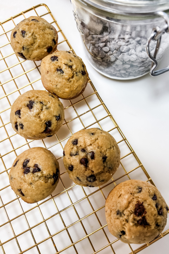 chocolate chip muffins on a cooling rack next to a jar of mini chocolate chips