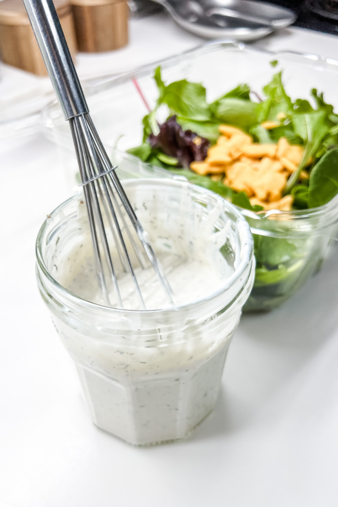 finished ranch dressing with a whisk and salad in the background