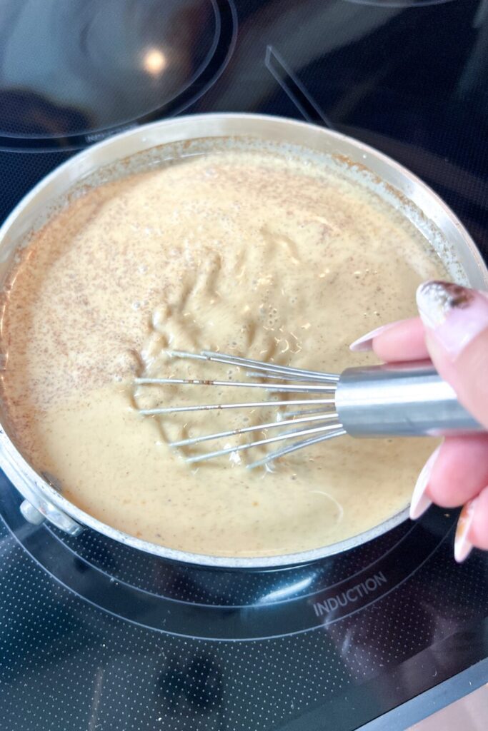 a person using a whisk to mix the Pumpkin Spice Coffee Creamer almost completely in a pot
