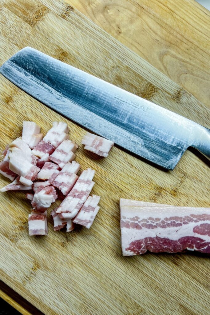 sliced bacon on a cutting board next to a knife