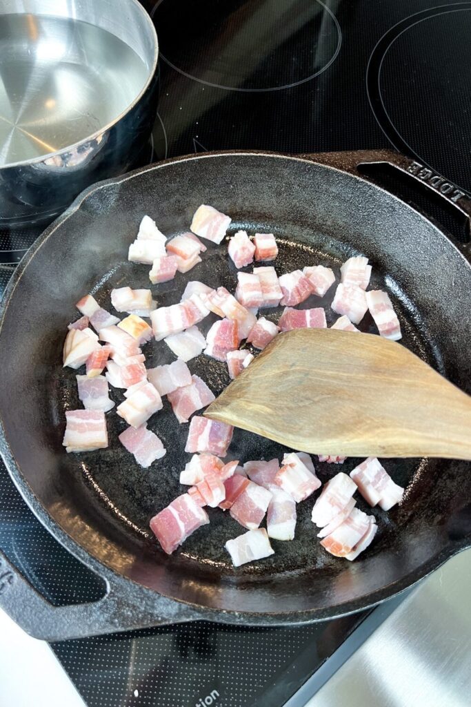 a pan with bacon cooking on top of a stove