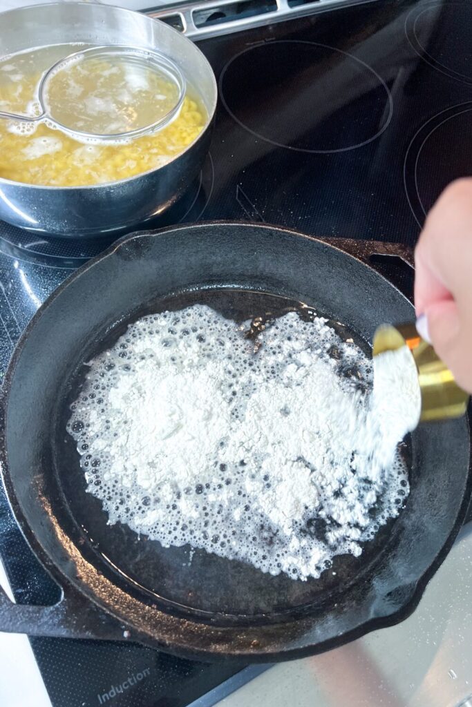 a person cooking flour in bacon fat in a frying pan on a stove