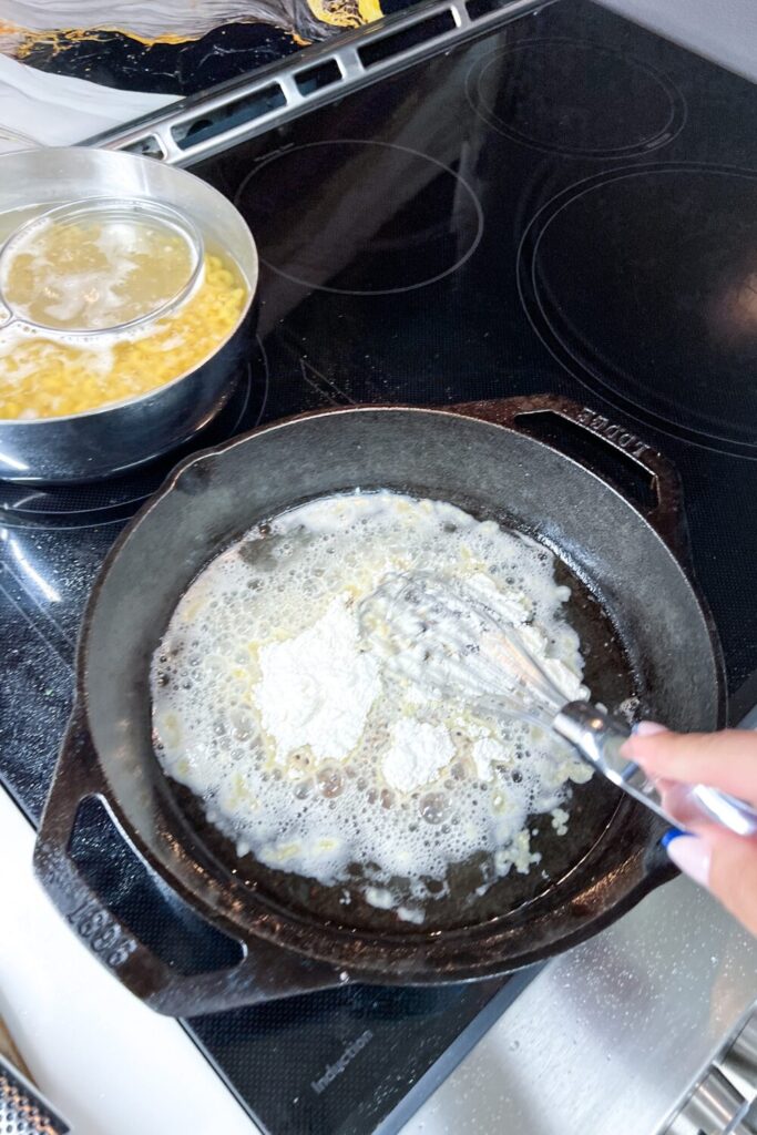 a person whisking the flour in the bacon fat in a skillet on a stove