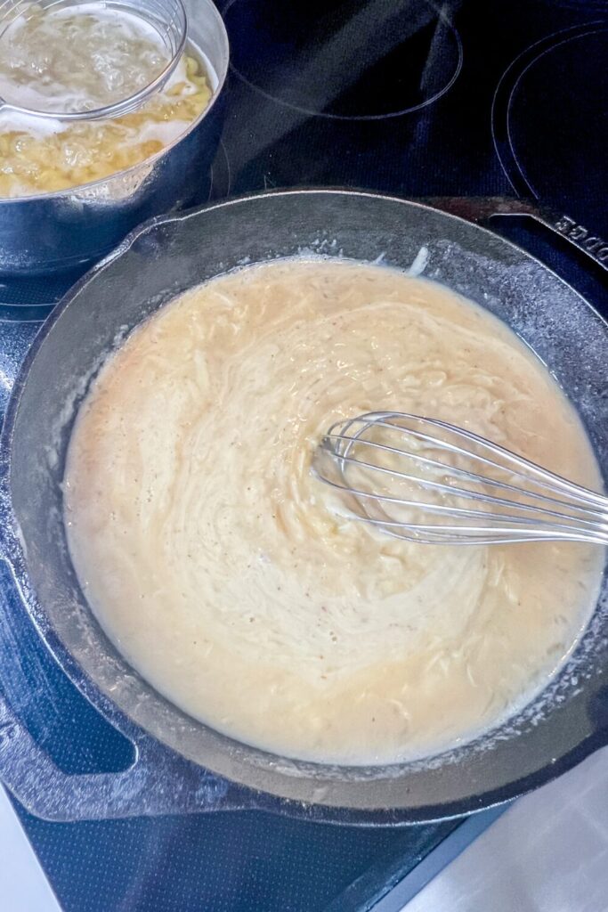 whisking the cheesy mixture in a skillet on top of a stove