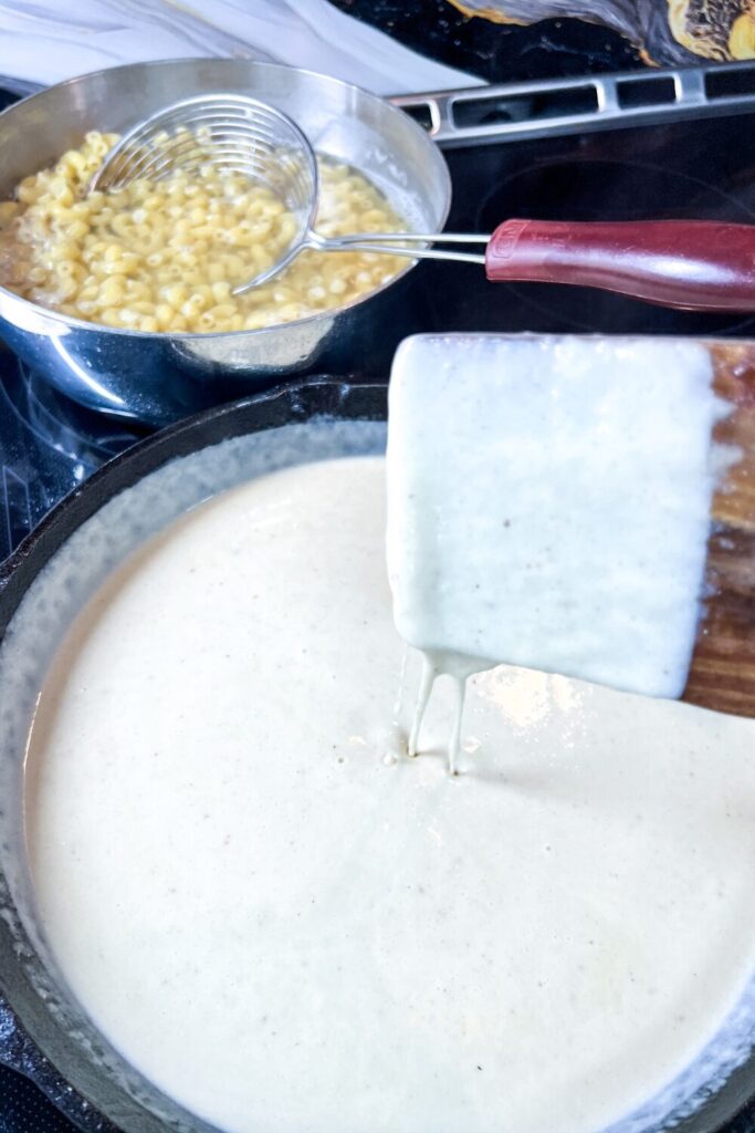 showing the consistency of the sauce on a wooden turner. It should be slightly stringy from the cheese.