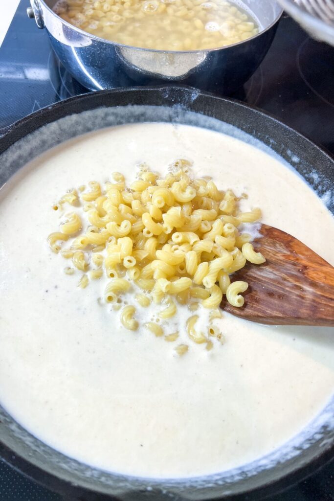 a pan filled with macaroni in cheese sauce on top of a stove