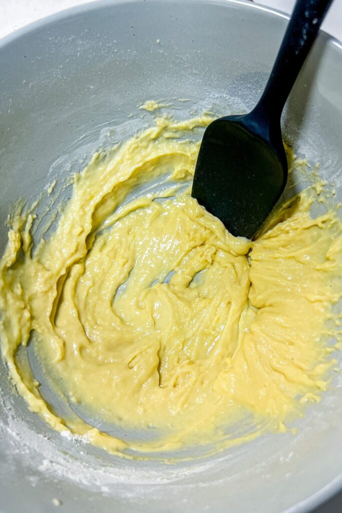a bowl of the potato pancake batter (before hashbrowns are added) with a spatula in it after being mixed