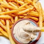 french fries with paprika mayo dipping sauce on a white plate One fry with sauce on it