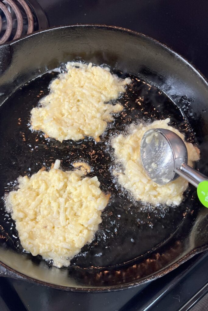 potato pancakes being cooked in a skillet on the stove