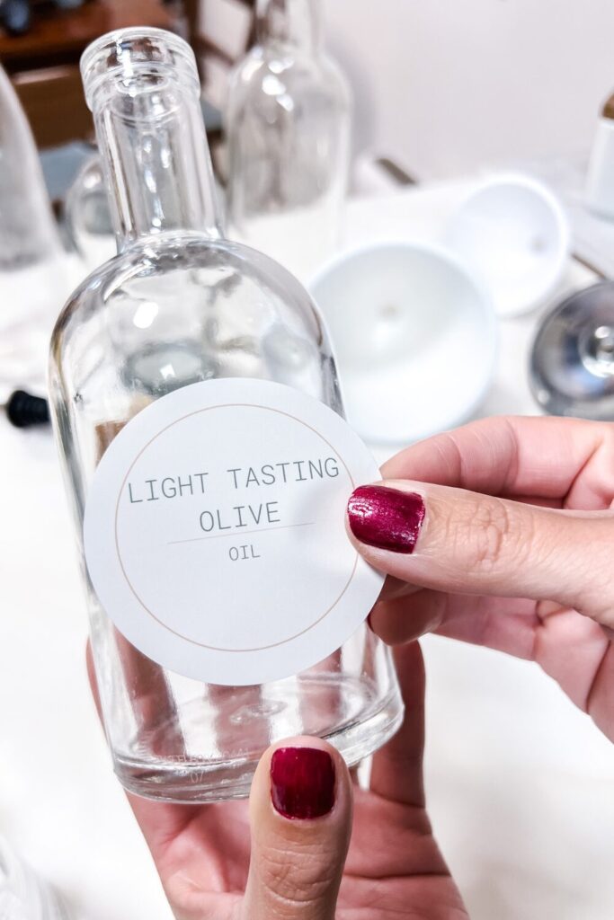 a person holding a bottle placing a light tasting olive oil sticker on the bottle