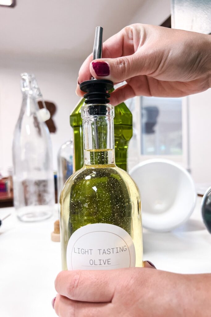a person is inserting an oil dispenser top into a bottle filled with oil - front view