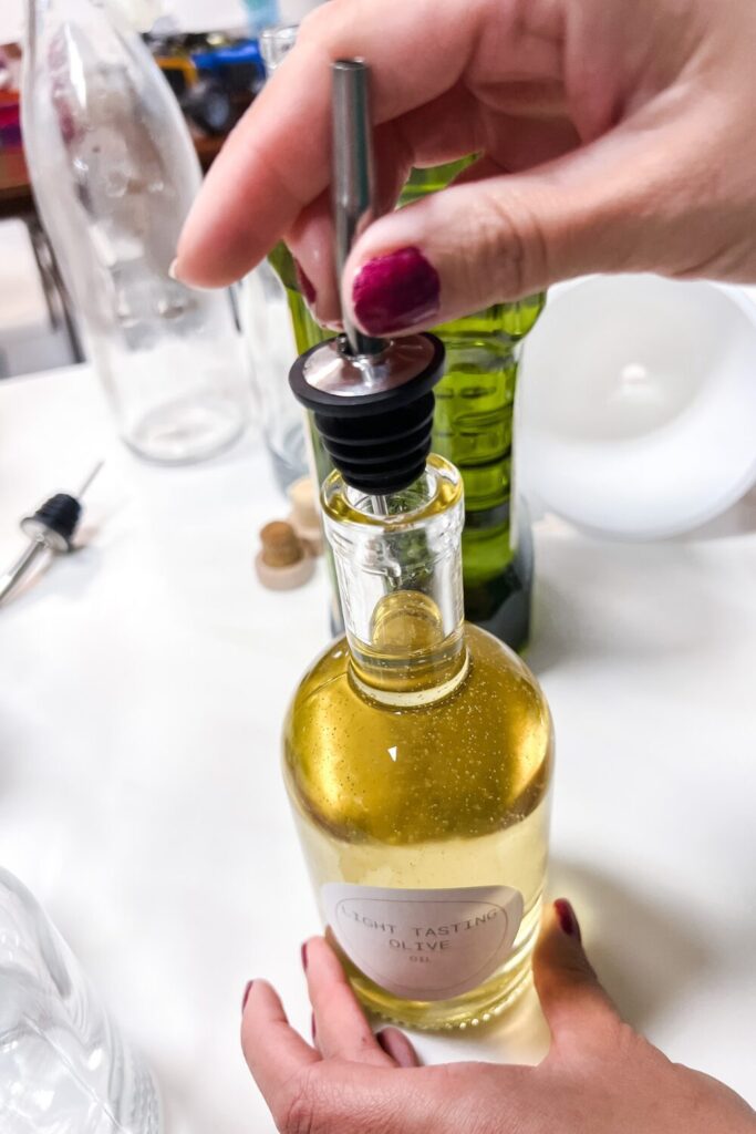 a person is inserting an oil dispenser top into a bottle filled with oil - top view