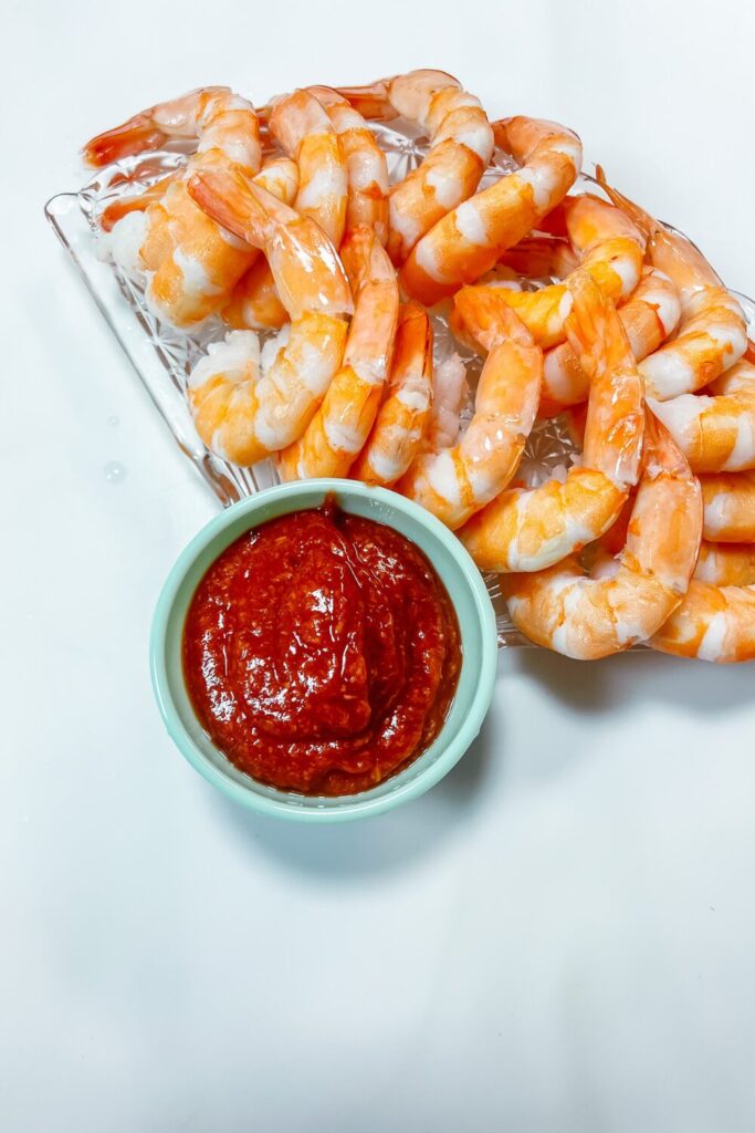 shrimp and sauce on a fan-shaped plate with a bowl of cocktail sauce at the bottom
