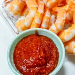 shrimp and sauce on a plate with a bowl of sauce