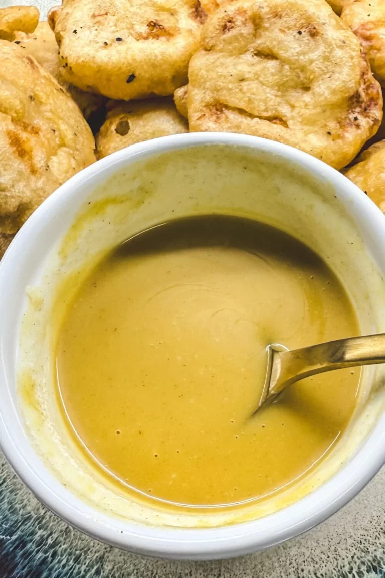 a bowl of honey mustard on a plate of chicken nuggets