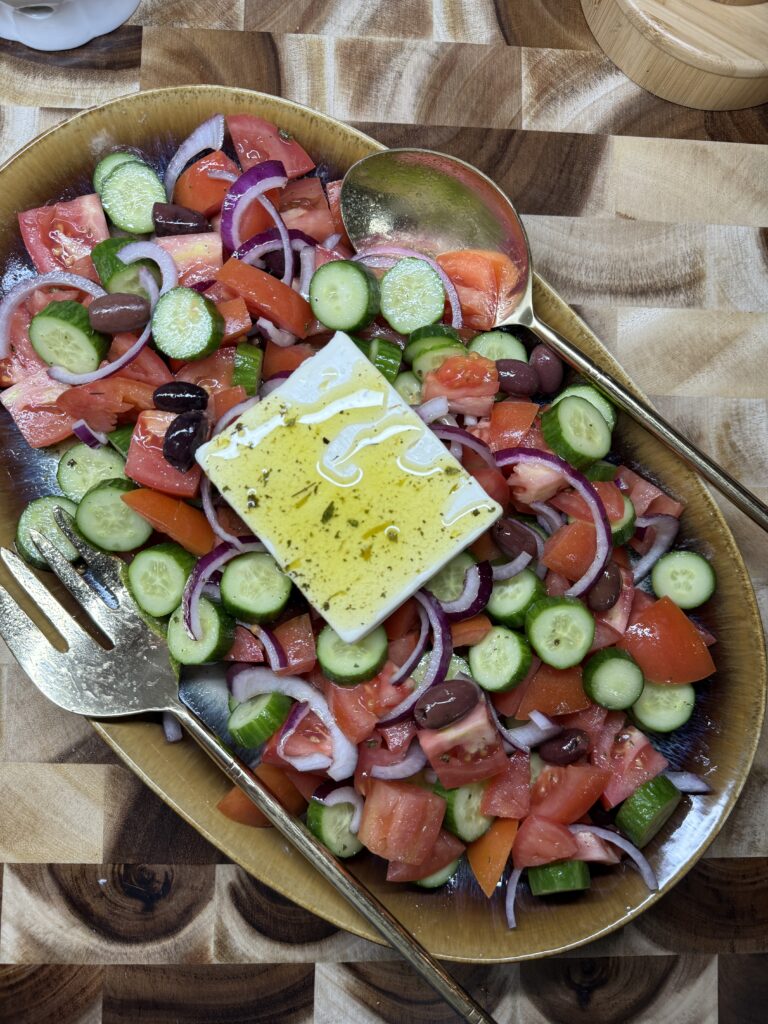 Greek Salad image with feta cheese on the top waiting to be broken up