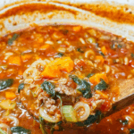 A person holding the Finsihed the Italian Ground Sausage Soup in a ladle over a pot of the soup