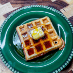 two plates with waffles topped with butter and syrup