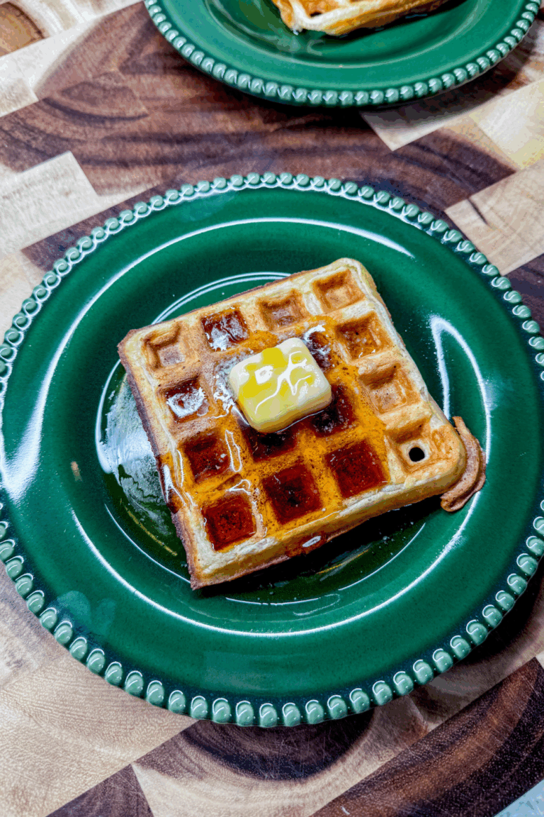 two plates with waffles topped with butter and syrup