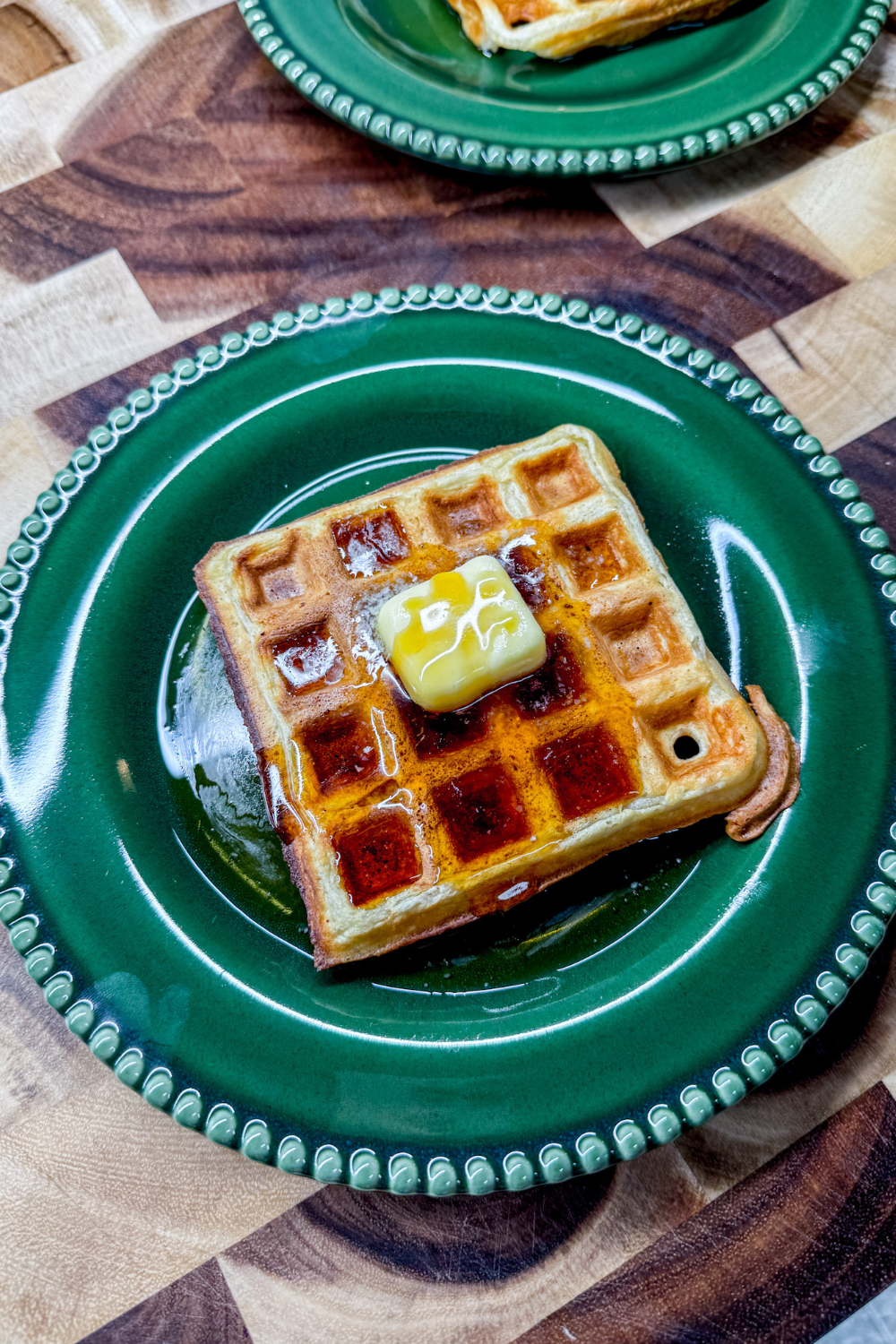 two plates with waffles topped with butter and syrup