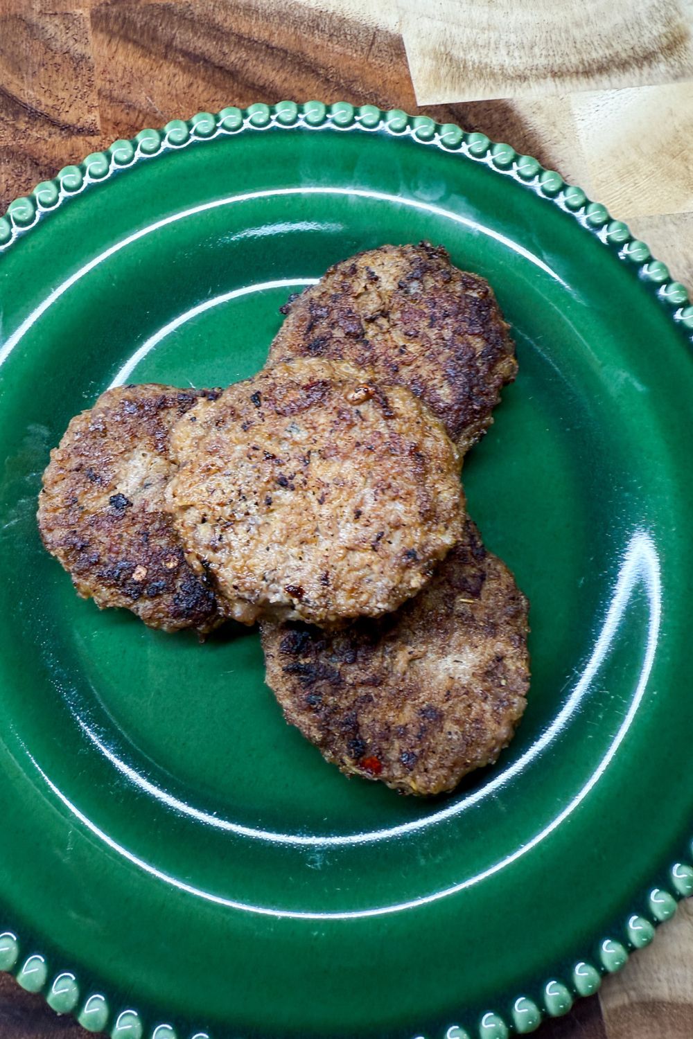Cooked homemade breakfast sausage patties served on a green plate