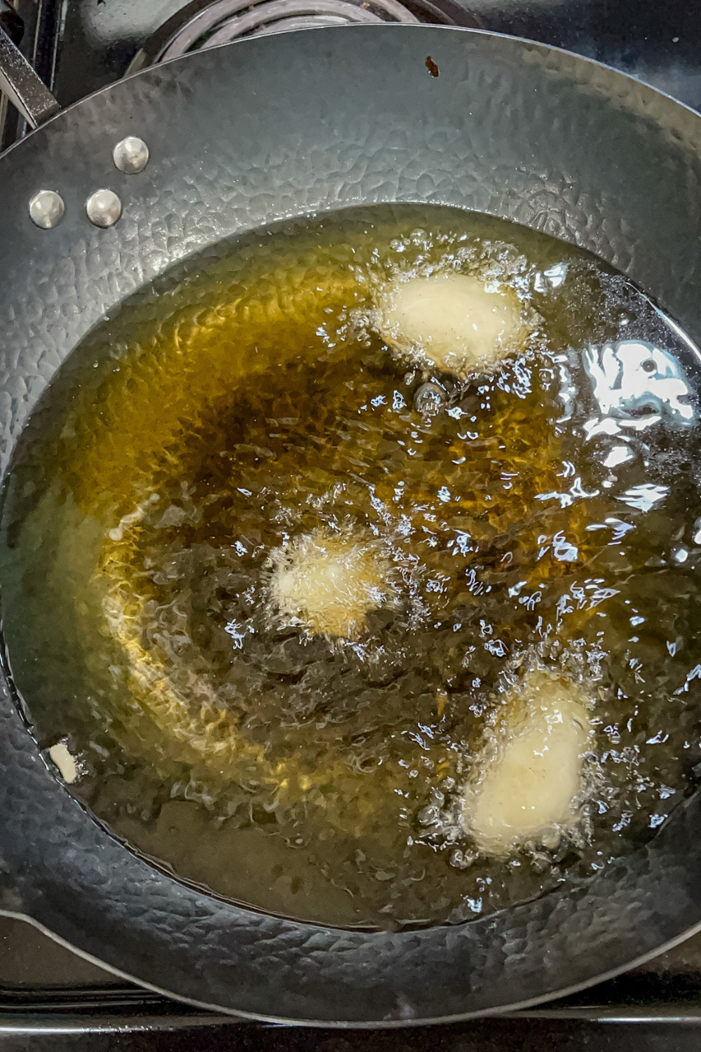 Cheese curds frying in peanut oil in a wok at high heat