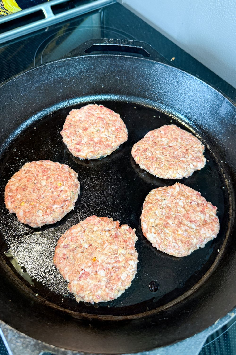 Breakfast sausage patties cooking in a cast iron skillet on the stovetop