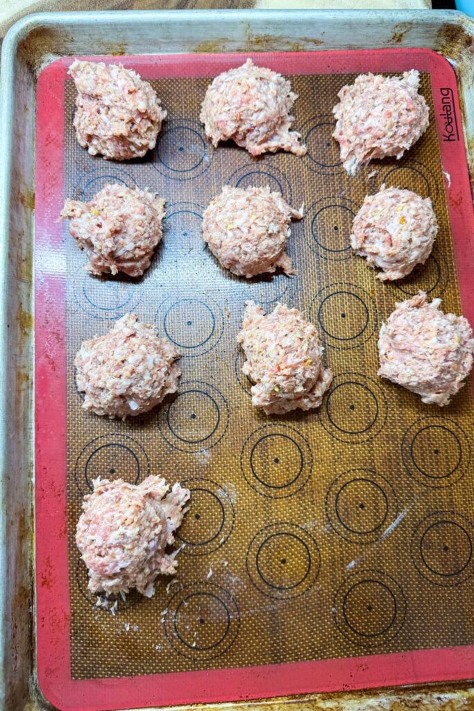 Breakfast sausage patties portioned with a scoop on a baking sheet before cooking
