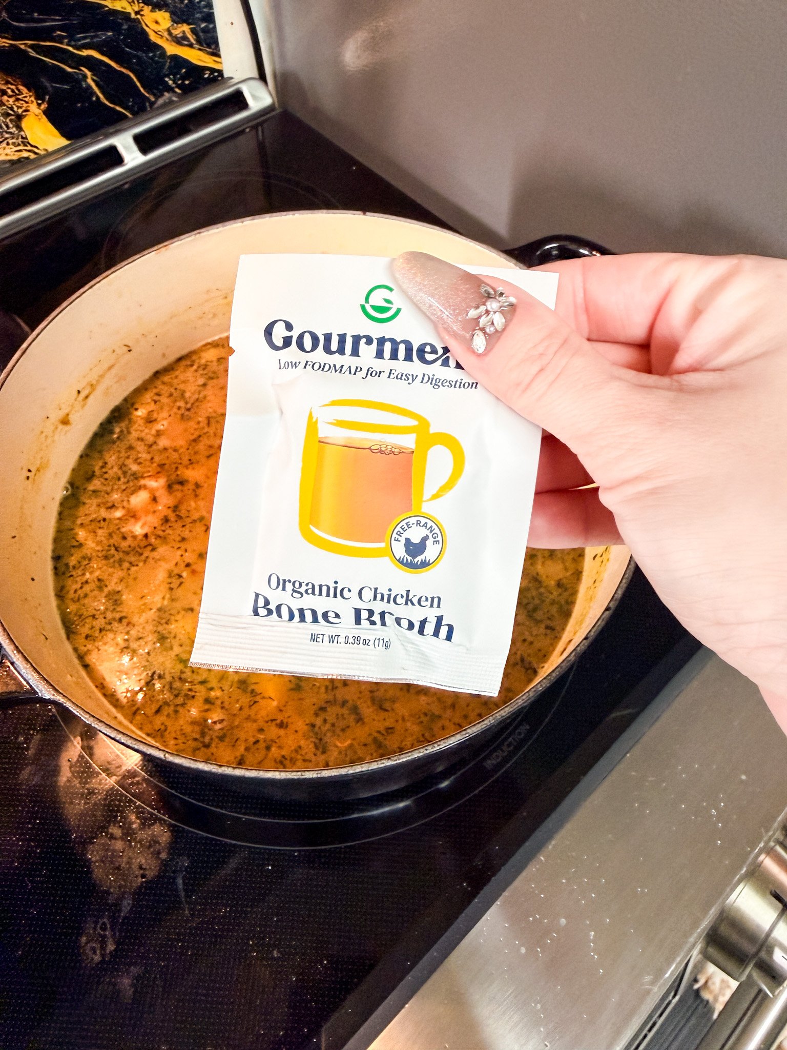 Chicken bone broth powder being added to homemade chicken and dumplings soup