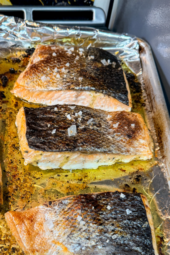 Oven-baked salmon with crispy skin on foil-lined baking sheet
