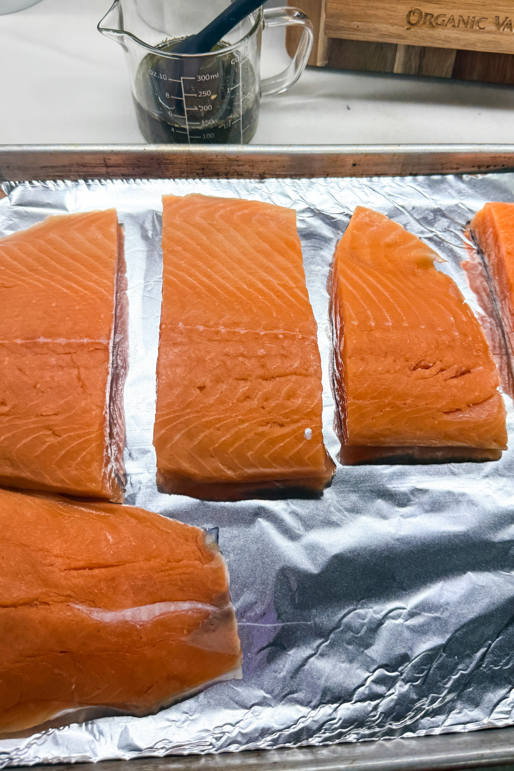 Raw salmon portions arranged on a foil-lined baking sheet before seasoning