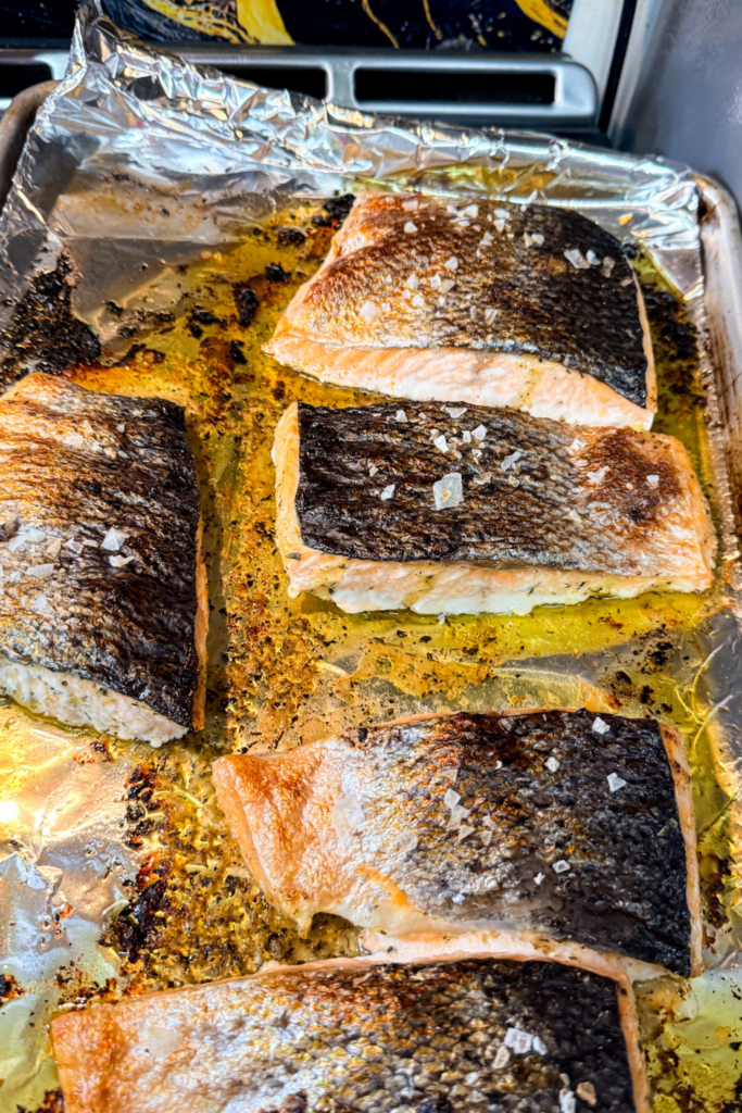Salmon skin topped with flaky sea salt before oven baking